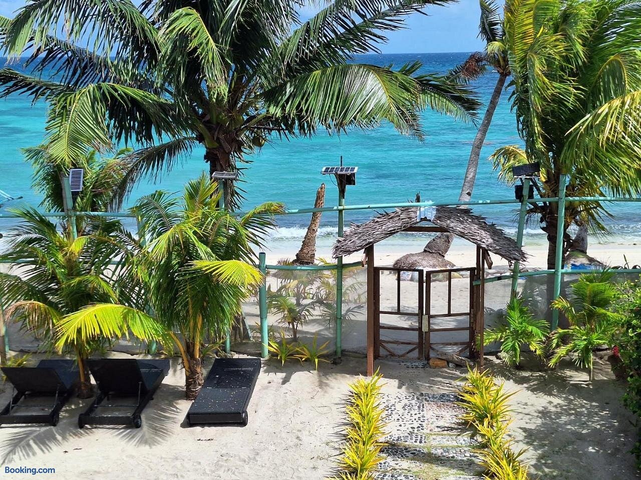 Beach access at Happy's Homestay — lounge chairs, thatched gate, and turquoise Tambisaan sea