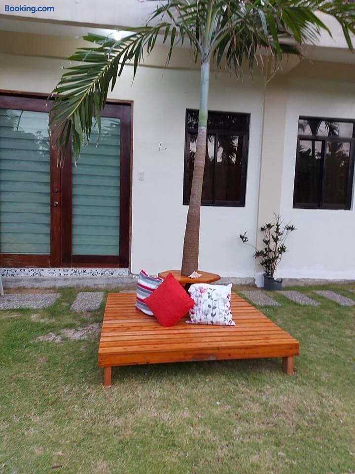 Outdoor lounge area at Happy's Homestay — wooden daybed on green lawn with palm tree