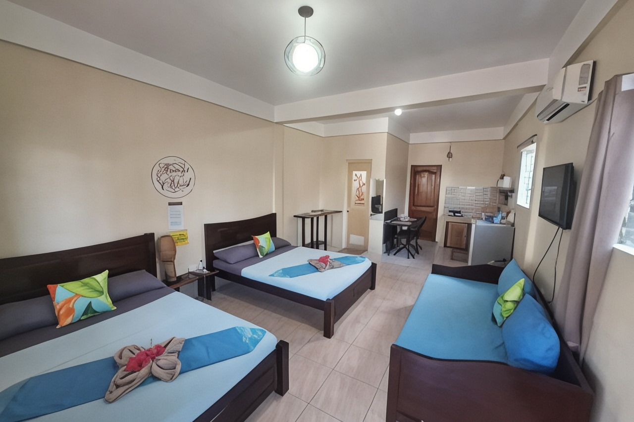 Family Room at Happy's Homestay — spacious with multiple beds, sofa, and kitchenette