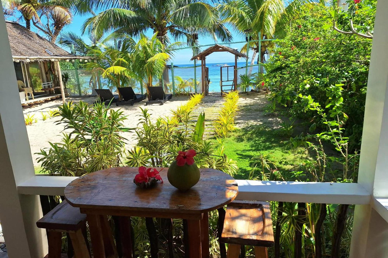 Balcony table with hibiscus flowers overlooking Tambisaan Beach garden