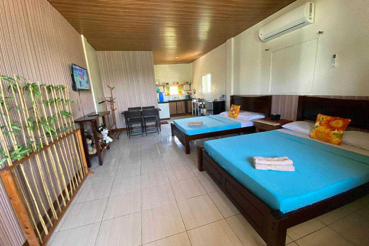 Family Room interior at Happy's Homestay — bamboo accent wall, teal bedding, kitchenette