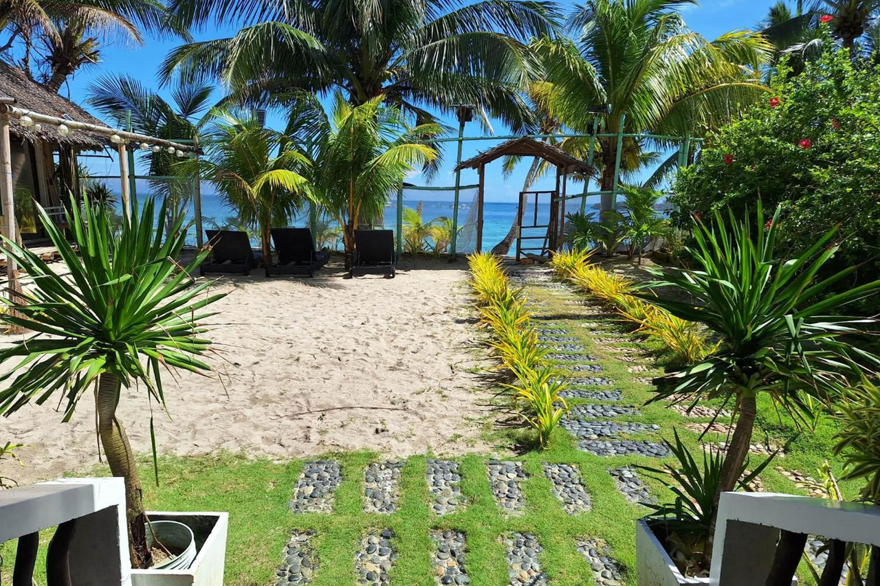 Garden pathway leading through the lawn to the beach, with sun loungers and the turquoise sea beyond